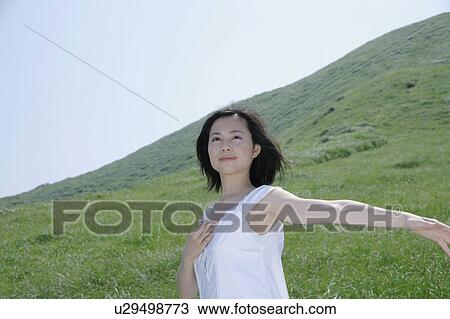 Stock Image - A young woman standing in field. Fotosearch
