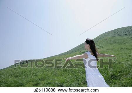 Stock Photo - A young woman standing in field. Fotosearch