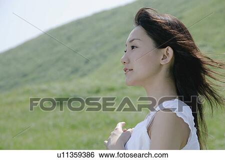 A young woman standing in field View Large Photo Image Stock Photograph - A young woman standing in field. Fotosearch