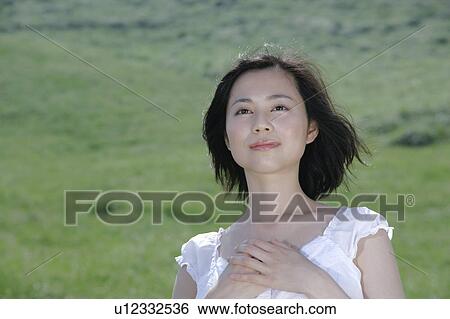 Stock Photograph - A young woman standing in field. Fotosearch