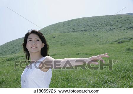 A young woman standing in field View Large Photo Image Stock Photography - A young woman standing in field. Fotosearch