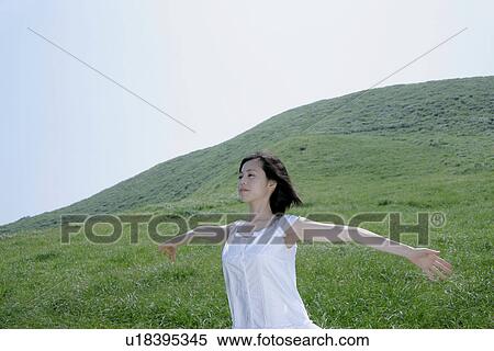 A young woman standing in field View Large Photo Image Stock Photography - A young woman standing in field. Fotosearch