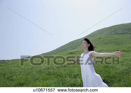 A young woman standing in field with her arms outstretched View Large Photo Image Stock Photo - A young woman standing in field with her arms outstretched. Fotosearch