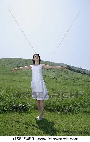 A young woman standing in field with her arms outstretched View Large Photo Image Stock Photo - A young woman standing in field with her arms outstretched. Fotosearch