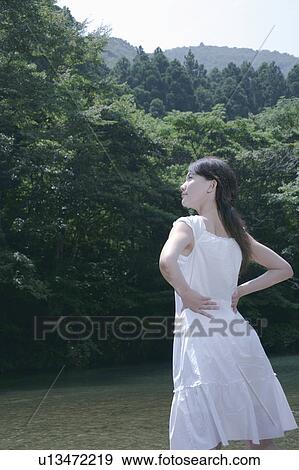 Stock Photo - A young woman standing in river. Fotosearch
