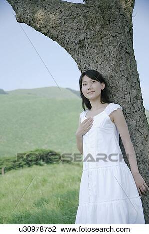 A young woman standing under tree View Large Photo Image Stock Image - A young woman standing under tree. Fotosearch