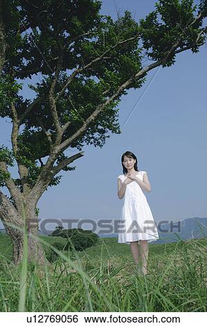 A young woman standing under tree View Large Photo Image Stock Photograph - A young woman standing under tree. Fotosearch