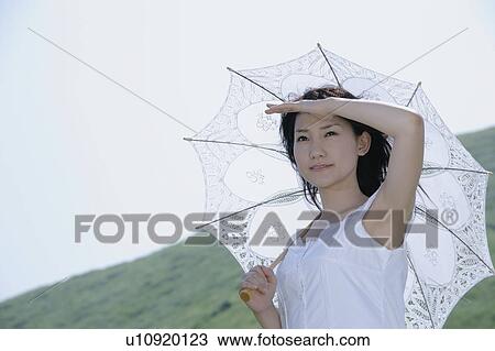 A young woman standing with parasol View Large Photo Image Stock Image - A young woman standing with parasol. Fotosearch
