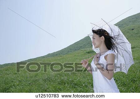 A young woman standing with parasol View Large Photo Image Stock Image - A young woman standing with parasol. Fotosearch