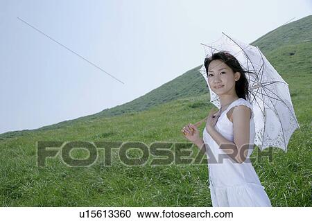 A young woman standing with parasol View Large Photo Image Stock Image - A young woman standing with parasol. Fotosearch