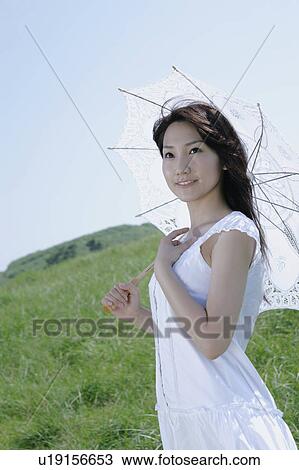 A young woman standing with parasol View Large Photo Image Stock Image - A young woman standing with parasol. Fotosearch