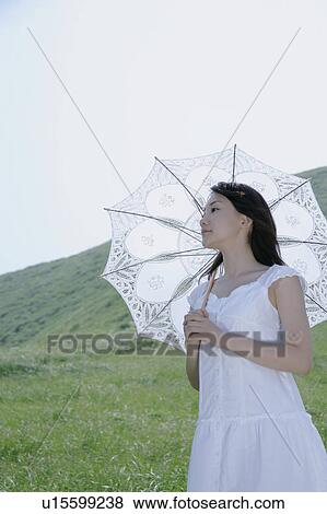 A young woman standing with parasol View Large Photo Image Stock Photo - A young woman standing with parasol. Fotosearch