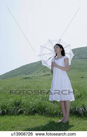A young woman standing with parasol View Large Photo Image Stock Photograph - A young woman standing with parasol. Fotosearch