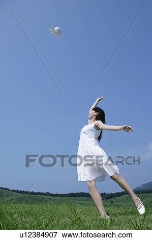 Stock Photo - A young woman throwing a hat. Fotosearch
