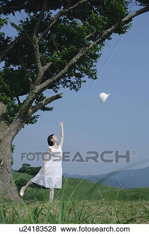 Stock Photo - A young woman throwing a hat. Fotosearch