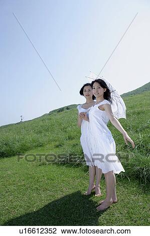 Stock Image - Two young women standing in field. Fotosearch