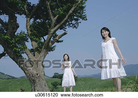 Two young women standing in field View Large Photo Image Stock Image - Two young women standing in field. Fotosearch