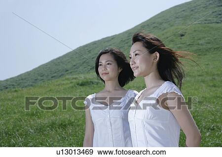 Two young women standing in field View Large Photo Image Stock Photo - Two young women standing in field. Fotosearch