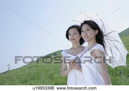 Two young women standing in field View Large Photo Image Stock Photograph - Two young women standing in field. Fotosearch