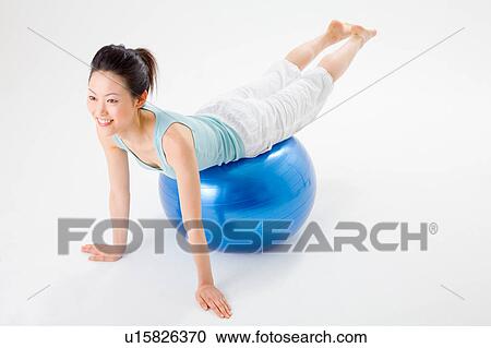Stock Image - Young woman doing push-ups on fitness ball. Fotosearch