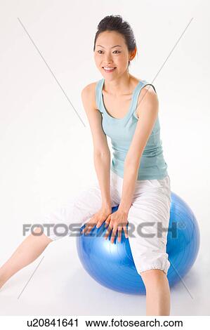 Stock Image - Young woman sitting on fitness ball. Fotosearch