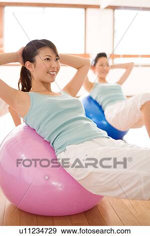 Young women lying on fitness balls doing sit-ups View Large Photo Image Stock Photo - Young women lying on fitness balls doing sit-ups. Fotosearch