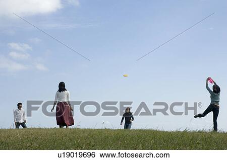 Stock Photograph - Four young people playing with flying disc. Fotosearch