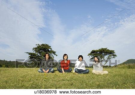 Four young people sitting in field View Large Photo Image Stock Photo - Four young people sitting in field. Fotosearch