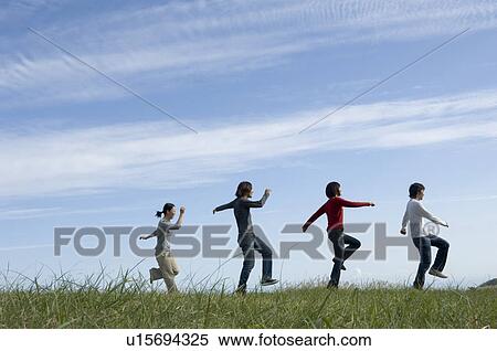 Four young people skipping in field View Large Photo Image Stock Photography - Four young people skipping in field. Fotosearch