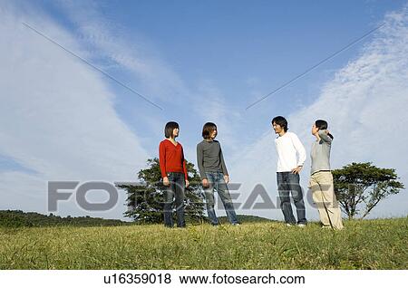 Four young people standing in field View Large Photo Image Stock Photo - Four young people standing in field. Fotosearch