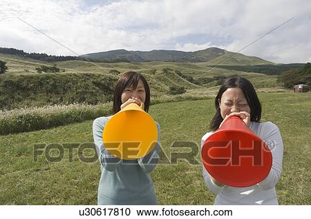 Two young women shouting into megaphones View Large Photo Image Stock Image - Two young women shouting into megaphones. Fotosearch