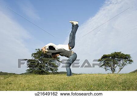 Young couple exercising back to back View Large Photo Image Stock Image - Young couple exercising back to back. Fotosearch