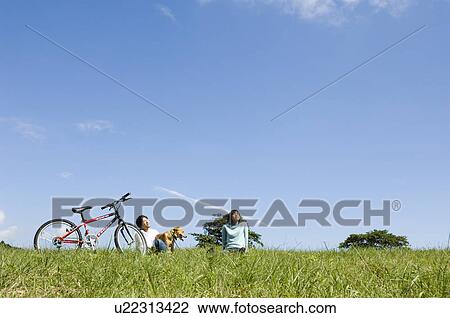 Stock Image - Young couple playing with dog. Fotosearch