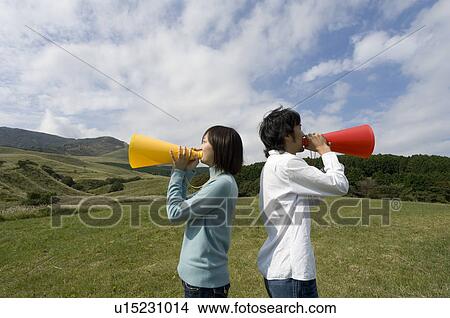 Picture - Young couple shouting into megaphones. Fotosearch