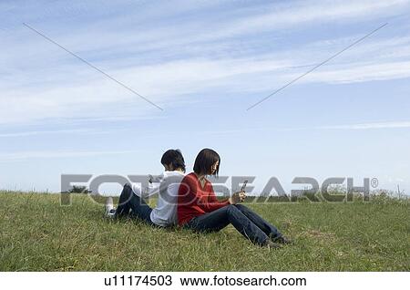Stock Image - Young couple sitting back to back. Fotosearch