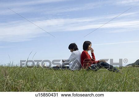 Young couple sitting back to back View Large Photo Image Stock Image - Young couple sitting back to back. Fotosearch
