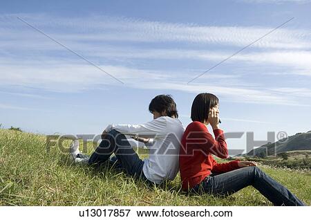 Young couple sitting back to back View Large Photo Image Stock Photo - Young couple sitting back to back. Fotosearch