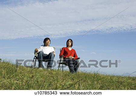 Stock Image - Young couple sitting in chairs. Fotosearch