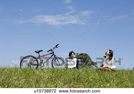 Stock Image - Young couple sitting next to bicycle. Fotosearch