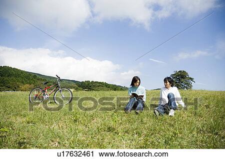 Young couple sitting on field View Large Photo Image Stock Image - Young couple sitting on field. Fotosearch