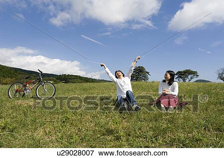 Stock Photo - Young couple sitting on field. Fotosearch