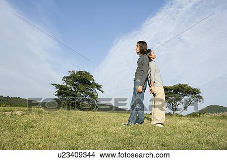 Young couple standing back to back View Large Photo Image Picture - Young couple standing back to back. Fotosearch