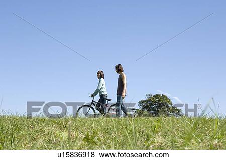 Young couple walking, woman pushing bicycle View Large Photo Image Stock Photo - Young couple walking, woman pushing bicycle. Fotosearch