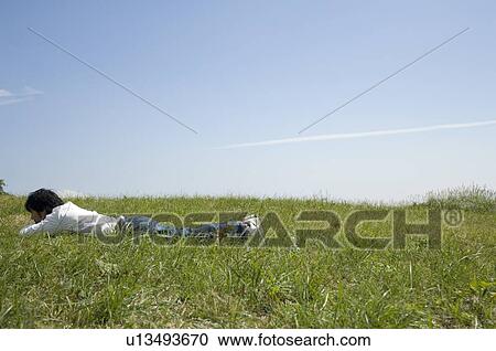 Young man lying down on field View Large Photo Image Stock Image - Young man lying down on field. Fotosearch