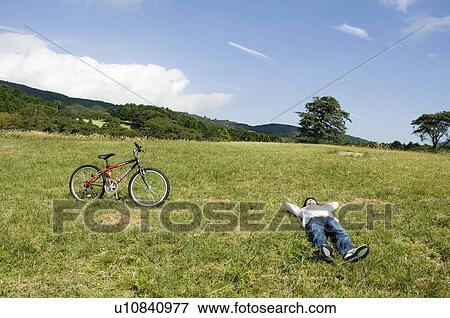 Young man lying down on field View Large Photo Image Stock Photo - Young man lying down on field. Fotosearch