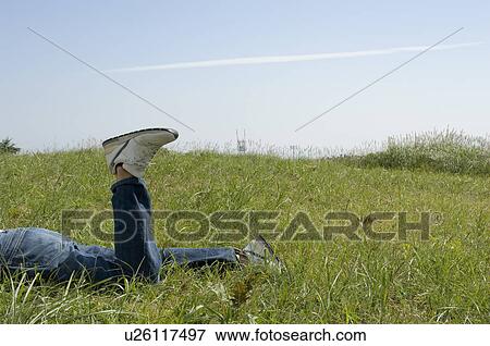Young man lying down on field View Large Photo Image Stock Photo - Young man lying down on field. Fotosearch