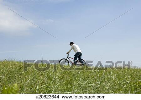 Young man pushing bicycle View Large Photo Image Picture - Young man pushing bicycle. Fotosearch