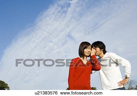 Young man whispering to young woman View Large Photo Image Stock Photograph - Young man whispering to young woman. Fotosearch
