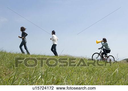 Young woman riding bicycle behind two young men running View Large Photo Image Stock Image - Young woman riding bicycle behind two young men running. Fotosearch