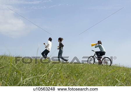 Young woman riding bicycle behind two young men running View Large Photo Image Stock Photo - Young woman riding bicycle behind two young men running. Fotosearch